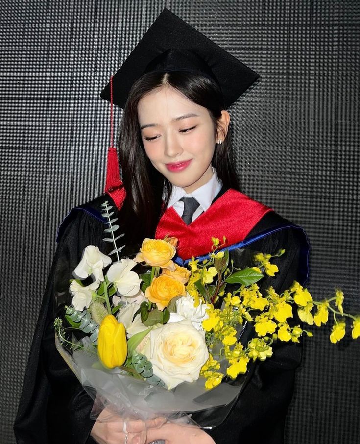 a woman in a graduation gown holding flowers