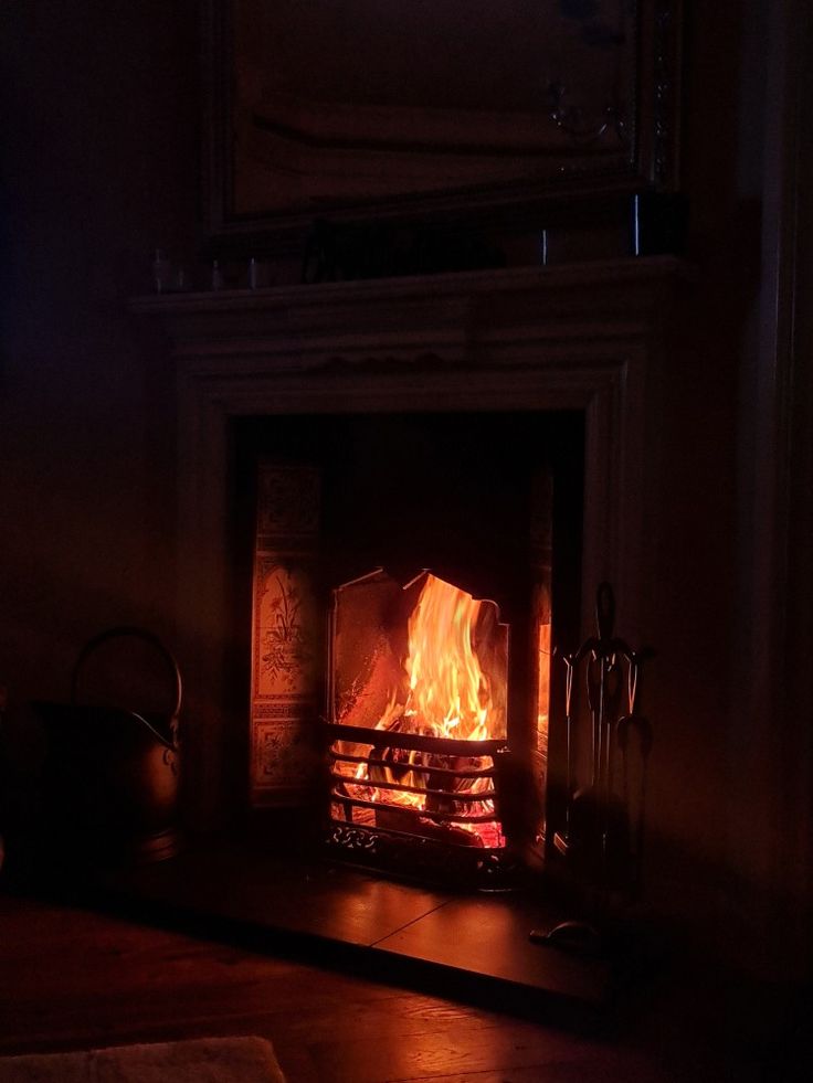 a lit fireplace in a dark room with the light on