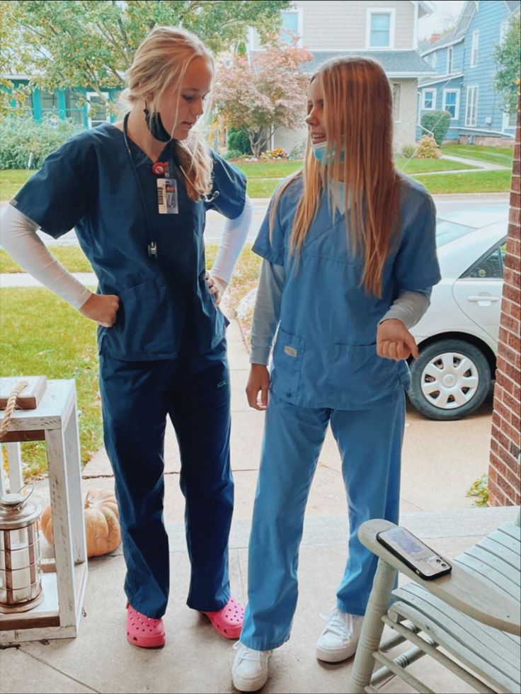 two women in scrubs are standing on the porch