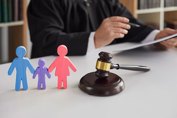 a judge sitting at a table in front of two paper cutouts of people and a gavel