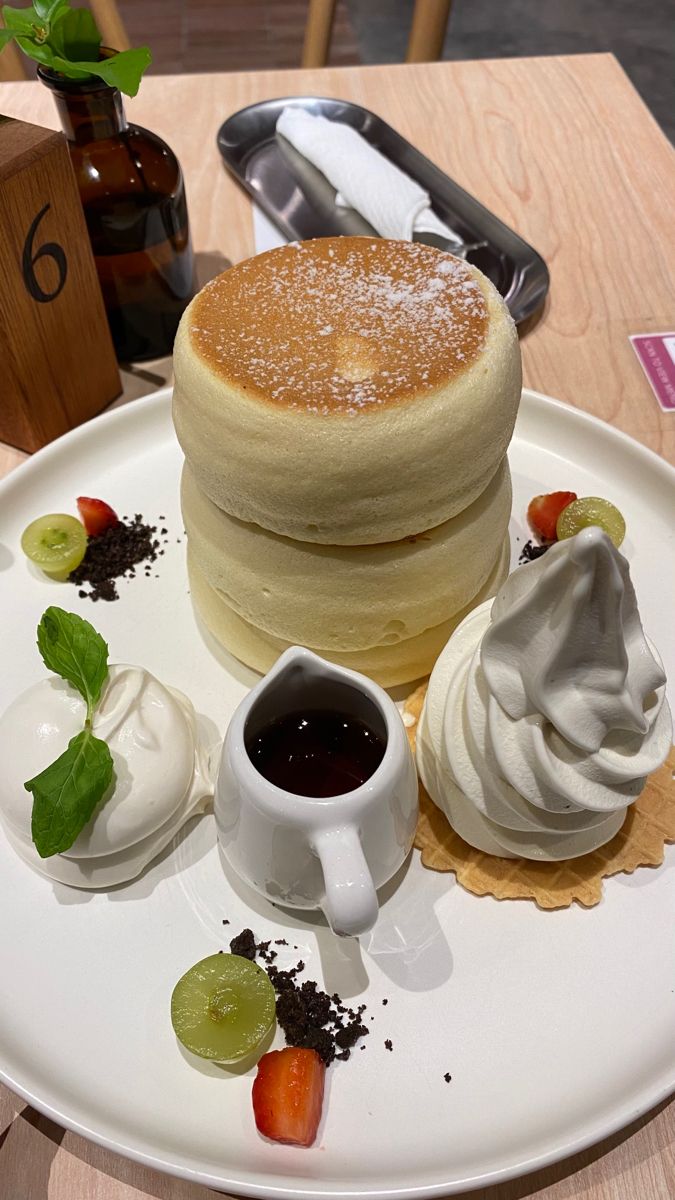 a white plate topped with pancakes covered in icing next to whipped cream and fruit