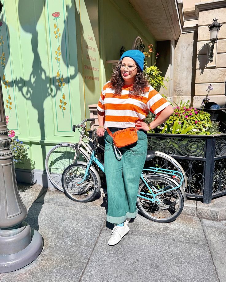 a woman standing next to a lamp post on the sidewalk with her bike behind her