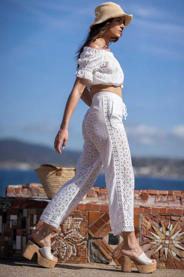 Notre pantalon d'été chic légèrement évasé. Fabriqué à partir d'un magnifique tissu en coton brodé, il est riche en détails. Les broderies de fleurs sur le côté et en bas ajoutent une touche de romantisme et d'élégance. Il dispose d'un élastique autour de la taille, pour s'ajuster à votre silhouette, ainsi que de deux poches avant. C'est un pantalon d'été original que vous pourrez porter avec nos hauts assortis Cloe ou Ashley, ou avec un débardeur ou une chemise basique. Pants White, Summer Pants, Cotton Pants, Embroidery Flowers, Basic Tank, Elastic Band, Basic Tank Top, Cotton Fabric, Tank Top