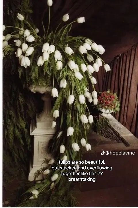 white flowers are hanging from the side of a pillar