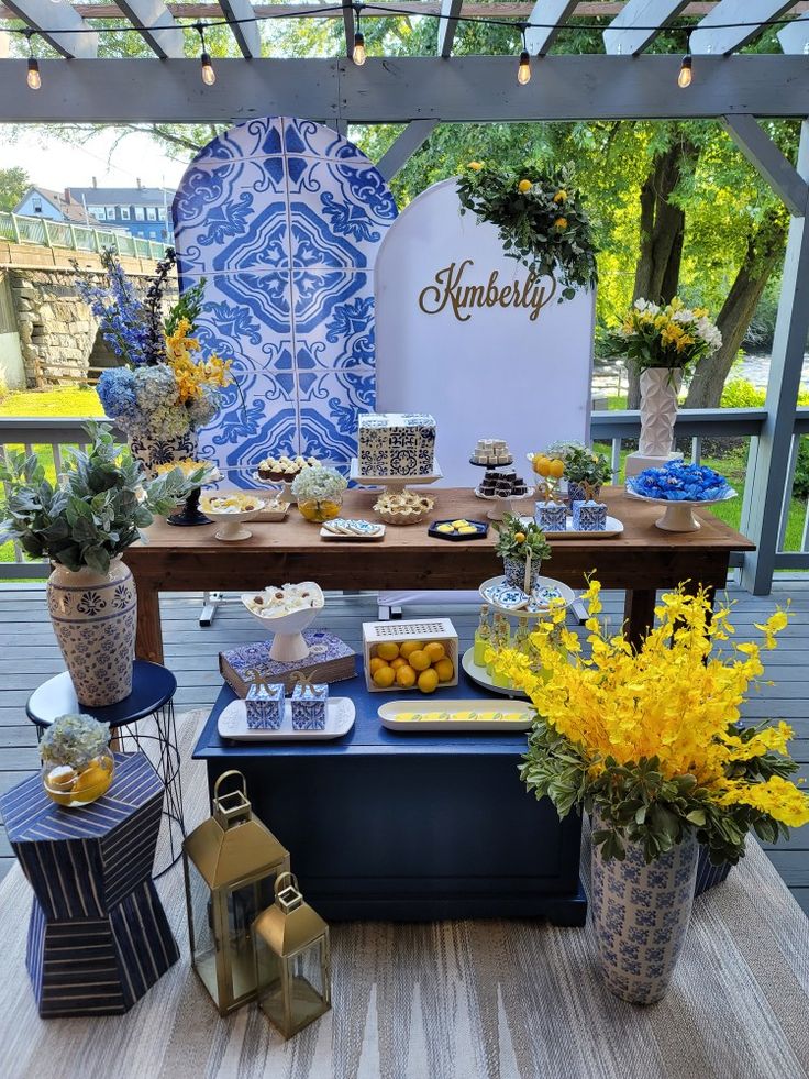 a blue and white dessert table with yellow flowers