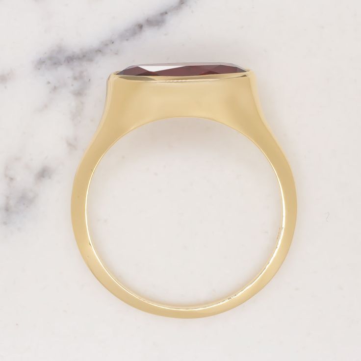 This beautiful and unique solitaire ring features a 2.19ct moval cut red garnet set in a sleek and elegant east west bezel setting! The garnet is a gorgeous rich red hue, and it has a beautiful play of light. The color is rich and luxurious, and it pairs perfectly with the yellow gold setting. The garnet’s elongated moval cut adds a unique touch. Combining aspects of the marquise cut and the oval cut, moval cuts are a rare find! The east west setting gives this classic ring a fashionable edge. A Formal Ruby Signet Ring With Bezel Setting, Modern Ruby Ring With Bezel Setting, Ruby Signet Ring With Bezel Setting For Formal Occasions, Formal Oval Cabochon Ruby Ring With Bezel Setting, Modern Yellow Gold Ruby Ring For Formal Events, Modern Yellow Gold Ruby Ring For Formal Occasions, Classic Ruby Ring With Tension Setting For Gift, Classic Ruby Ring With Tension Setting As Gift, Gold Ruby Ring With Tension Setting For Formal Occasions