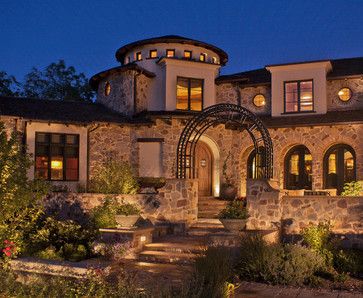 a large stone house lit up at night with lights on the front and side windows