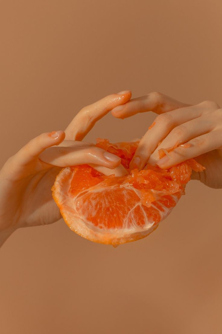 two hands holding an orange in the air