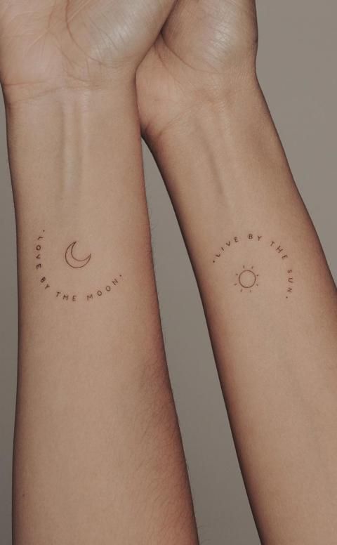 two people with matching wrist tattoos holding each other's hands and looking at the sky