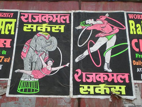 two posters on the side of a building advertising circus shows an elephant and a woman