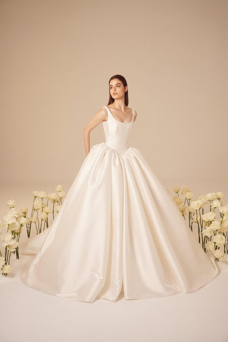 a woman in a white wedding dress standing next to flowers