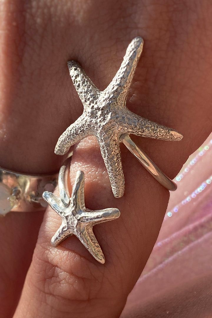 Two sea star lovers whisper to each other as they encircle your finger in this beautiful and delicate sterling silver wrap ring. Available in silver and gold plate silver. This piece is MADE TO ORDER by our in-house designer and owner, for up to date lead times please check the top of the collection page. If you would like to request priority for a special occasion please email info@stonehartjewelry.com, we can usually accommodate. Custom inquiries email info@stonehartjewelry.com Sea Inspired Accessories, Silver Starfish Jewelry As Gift, Silver Starfish Jewelry For Gifts, Silver Starfish Charm Jewelry, Rock Barbie, Silver Starfish-shaped Jewelry Gift, Ocean-inspired Jewelry With Starfish Charm And Shell Shape, Sea Rings, Starfish Ring