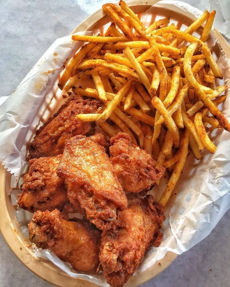 fried chicken and french fries are in a basket on the table, ready to be eaten