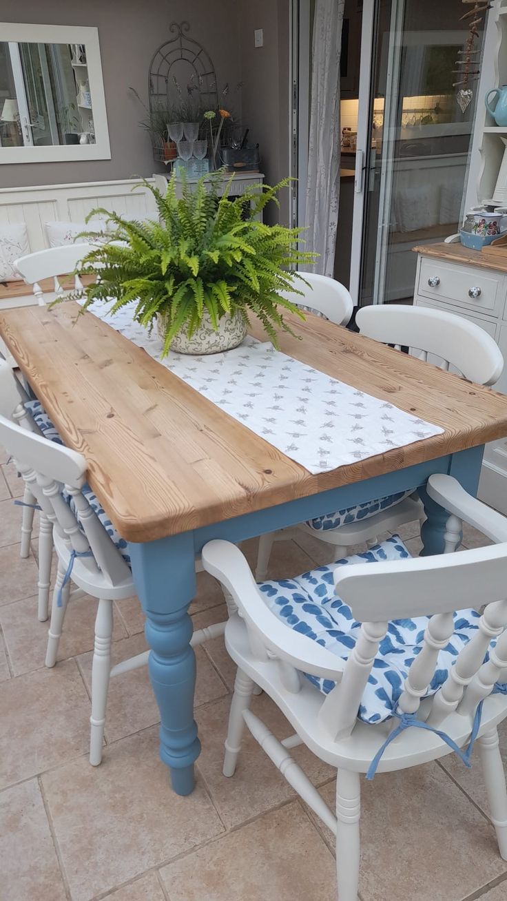 a wooden table with chairs around it and a potted plant on top of it