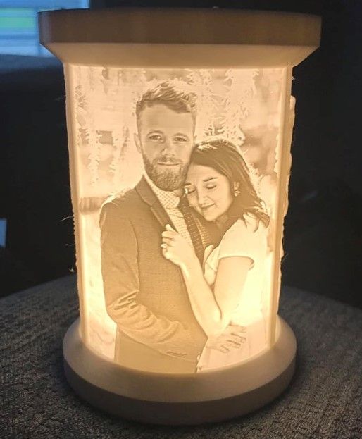 an illuminated photo is shown in the shape of a candle with a couple on it