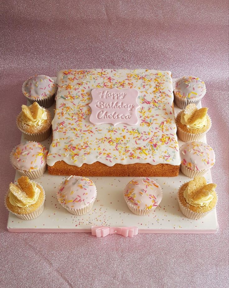 a birthday cake surrounded by cupcakes on a plate