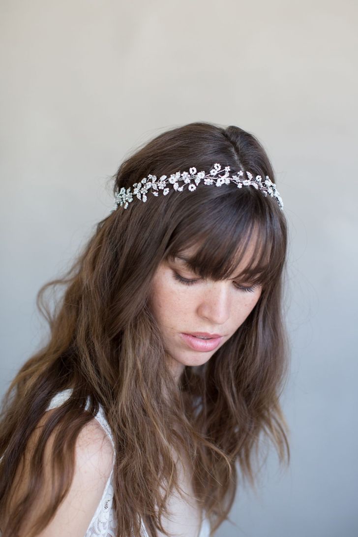 a woman with long hair wearing a headband made out of pearls and leaves on her head