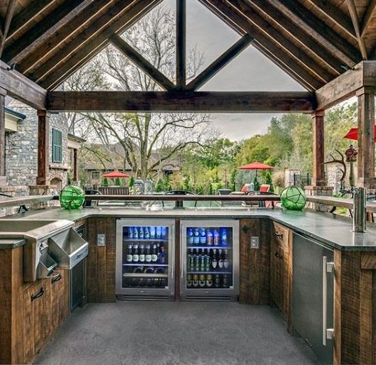 an outdoor kitchen with stainless steel appliances and wood cabinets, is pictured in this image