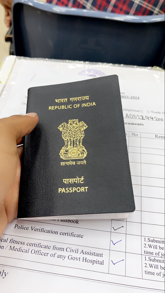 a person holding a passport in their hand and sitting at a table with other people