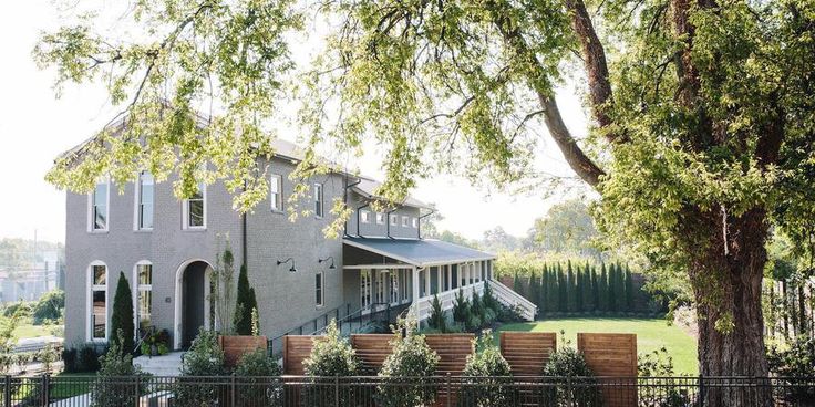 a large house sitting on top of a lush green field next to a fenced in yard