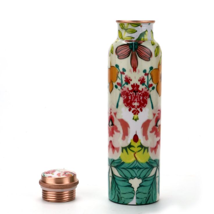 a vase with flowers and leaves painted on it next to a copper coin bank in the shape of a flower