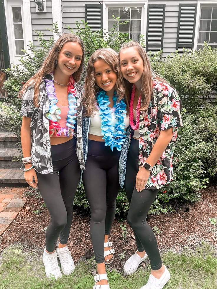 three girls standing next to each other in front of a house with flowers on them