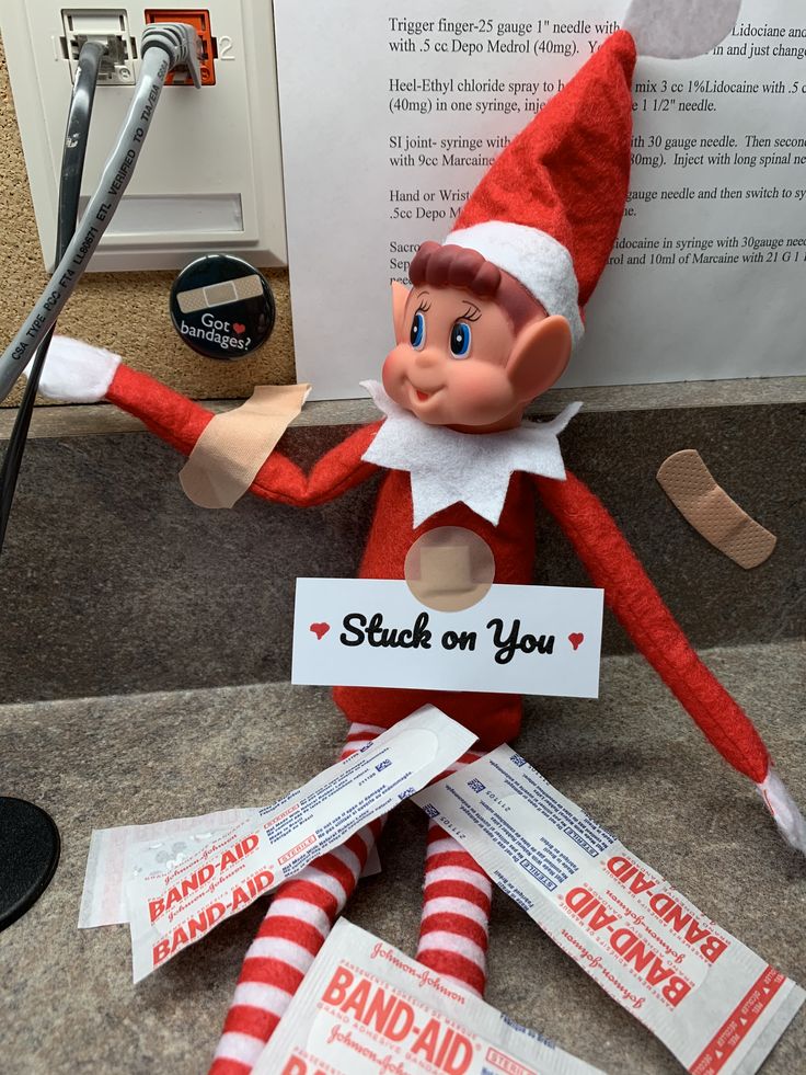 an elf is sitting on the ground with some candy in front of him and holding a sign that says stuck on you