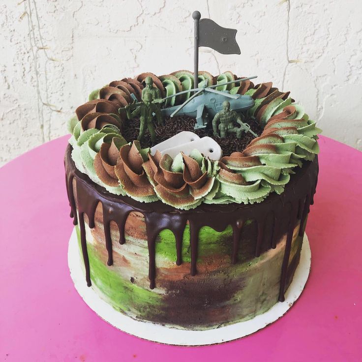 a birthday cake with chocolate icing and green leaves on the top, sitting on a pink table