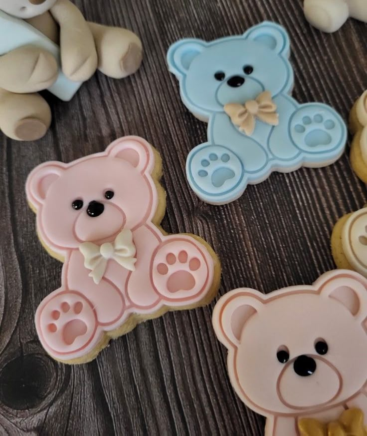 teddy bear cookies with fondant decorations on a wooden table next to small teddy bears