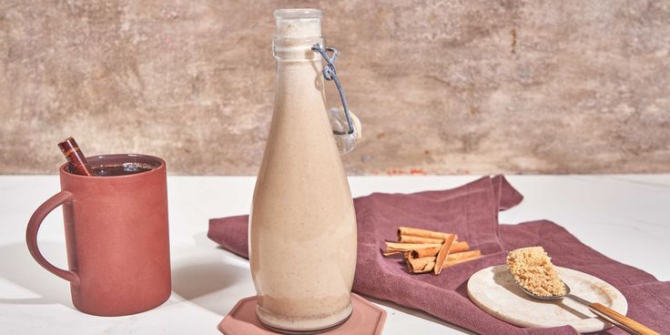 a bottle and mug sitting on top of a table next to a plate with food