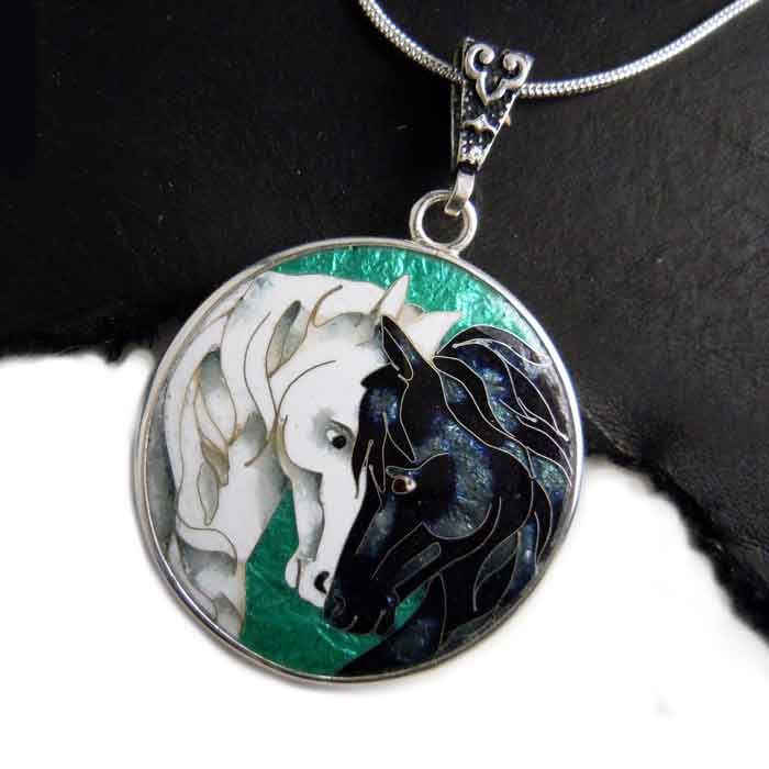 two horses are depicted in this hand painted glass caballon on a silver chain