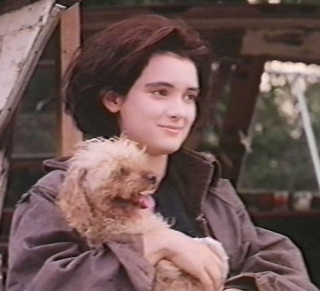 a woman holding a small dog in her arms and looking at the camera while sitting down