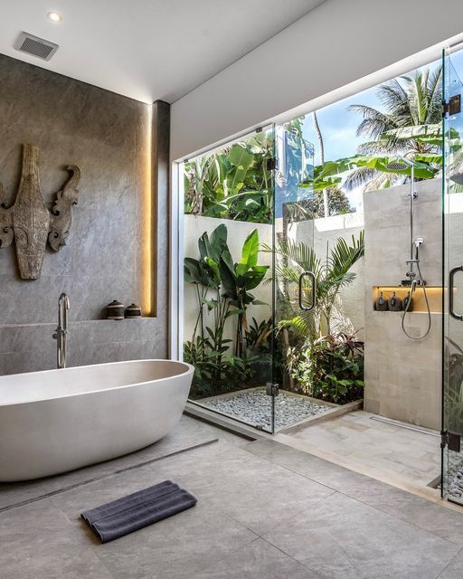 a bathroom with a large bathtub next to a walk in shower and glass walls