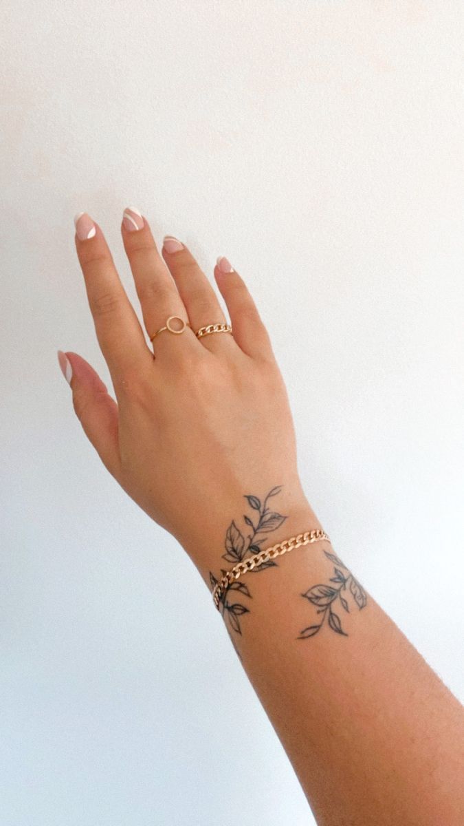 a woman's hand with tattoos on it and a gold chain around her wrist