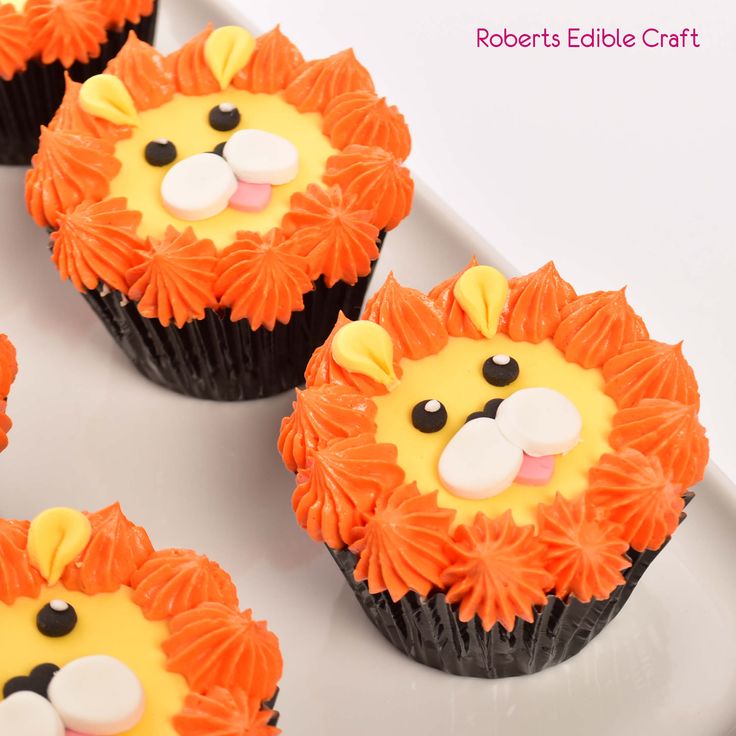 four cupcakes decorated like lions on a plate