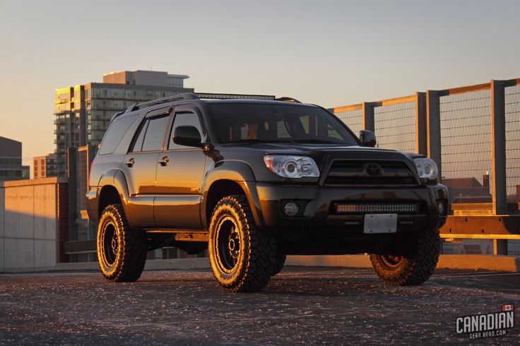 a black four - doored suv parked in front of a building with tall buildings