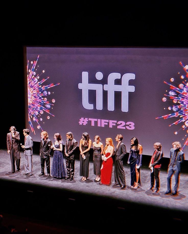 a group of people standing on top of a stage with fireworks in the sky behind them