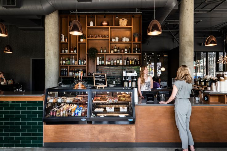 two women standing in front of a counter at a coffee shop