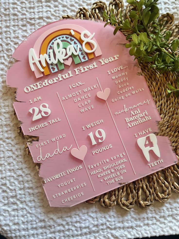 a pink and white calendar sitting on top of a table next to a potted plant