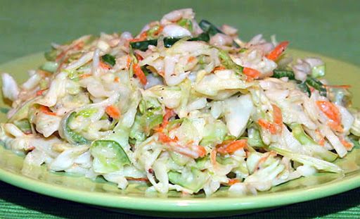 a green plate topped with coleslaw and carrots on top of a table