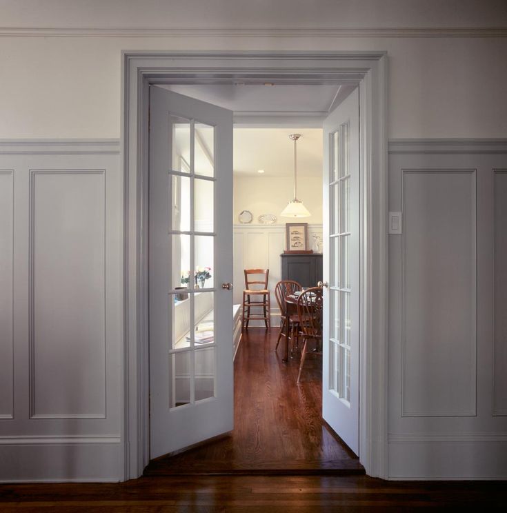 an open door leading to a kitchen and dining room with hard wood flooring on both sides