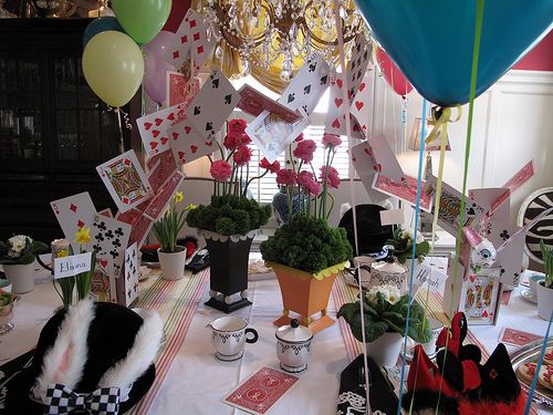 a table topped with lots of balloons and cards next to a vase filled with flowers