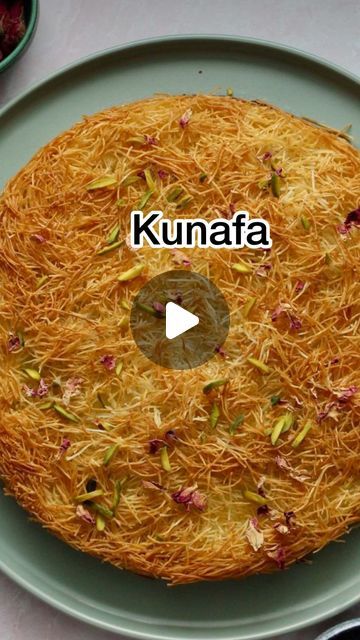 a round cake on a green plate with the words kunnafa in front of it