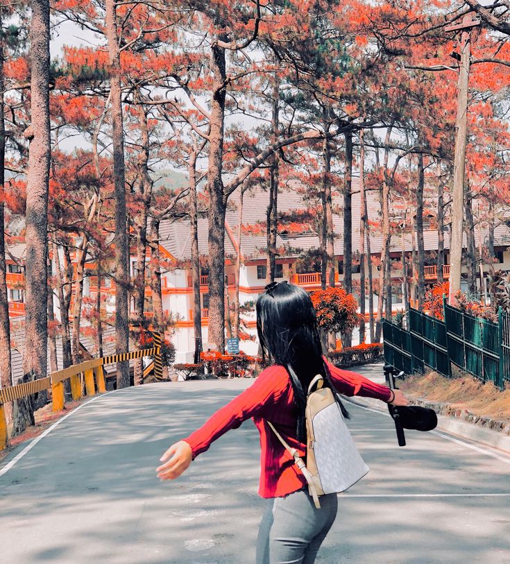 a young woman riding a skateboard down a street next to trees with orange leaves