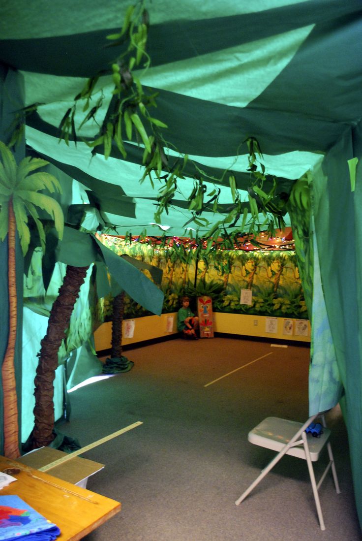 the inside of a tent with tables and chairs under it, next to palm trees