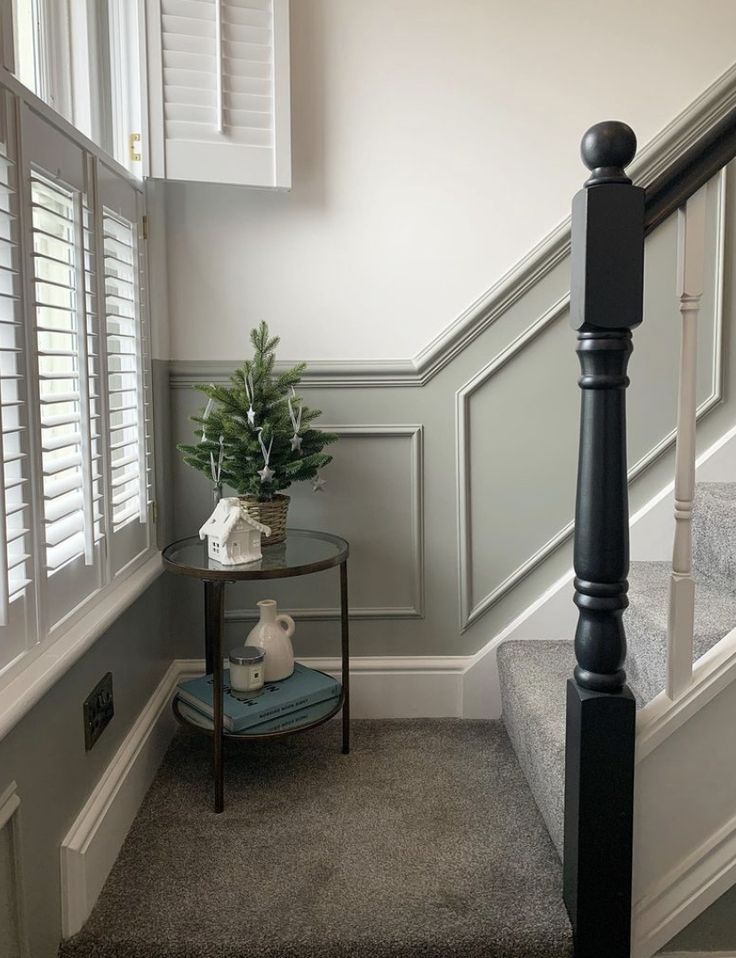 a small table with a potted plant on it next to some stairs and windows