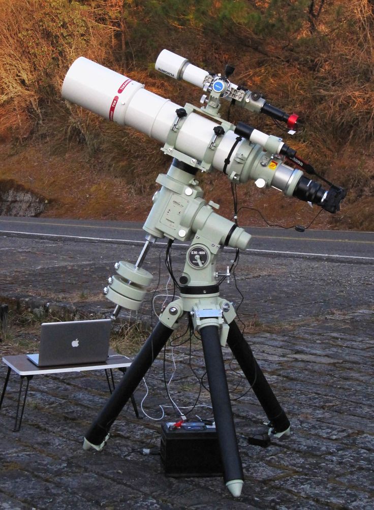 a telescope sitting on top of a table next to a laptop