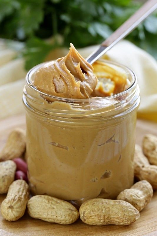 peanut butter in a jar with peanuts around it