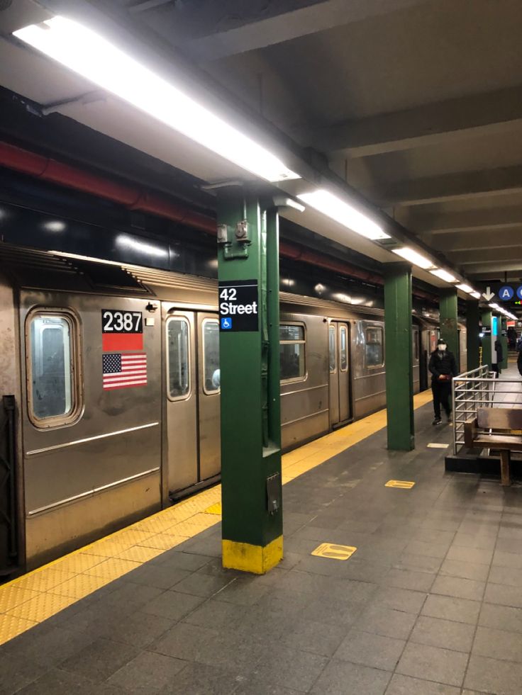 a subway station with people waiting for the train to stop at it's doors