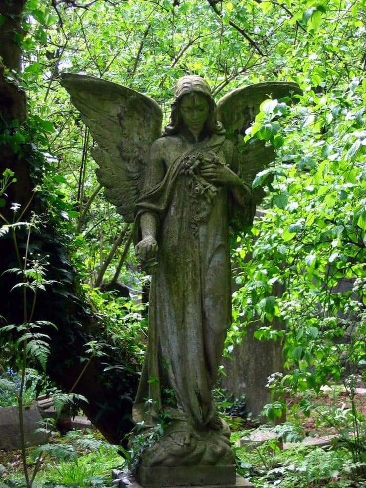 an angel statue in the middle of a forest